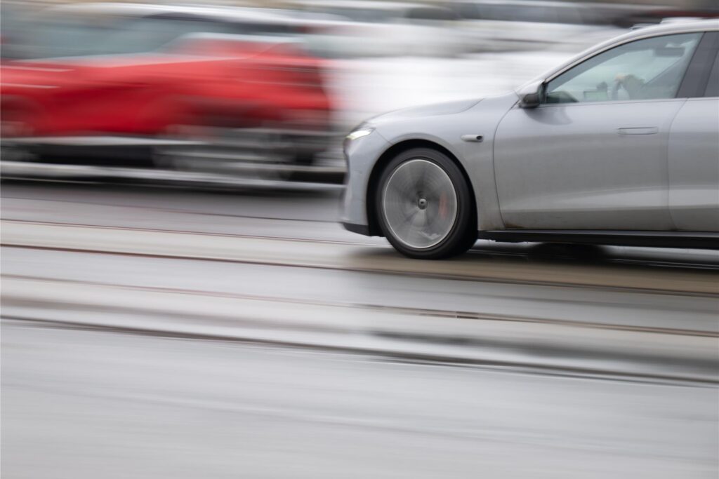 Ein rotes und ein graues Auto fahren schnell aneinander vorbei. Ein rotes und ein graues Auto fahren schnell aneinander vorbei.