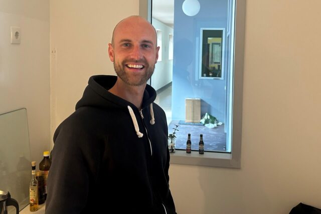 Lukas Heine vor dem Fenster zum Flur an der Kochnische seiner neuen Wohnung in der früheren Abendrealschule.