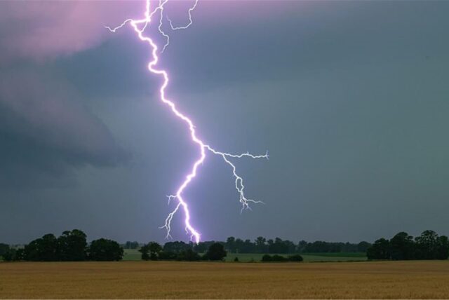 Ein Blitz schlägt in ein Feld ein.