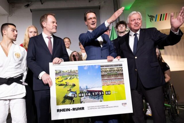 Hendrik Wüst (2.v.r, CDU), Ministerpräsident von Nordrhein-Westfalen, Volker Bouffier (r), Vorstand für besondere Aufgaben des DOSB, und Stephan Keller (CDU), Oberbürgermeister von Düsseldorf, halten ein Foto bei der Vorstellung des Konzepts einer Olympia-Bewerbung mit der Rhein-Ruhr-Region für die Olympischen Spiele.