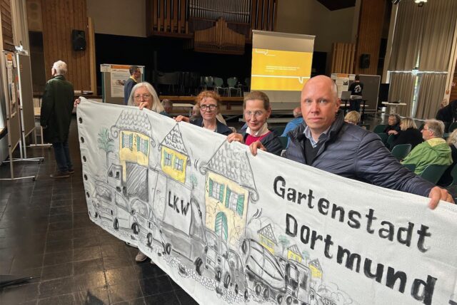 Vier Vertreter der Bürgerinitiative „Freunde der Gartenstadt“ halten ein Transparent, mit dem auf die Verkehrsprobleme in der Gartenstadt aufmerksam gemacht wird.