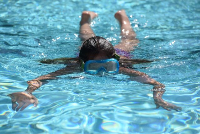 Ein Mädchen taucht durch das Wasser des Freibad Bornekamp.
