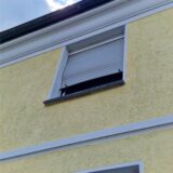 Eine Fensterrollo ist nach dem Brand eines Autos verzogen.