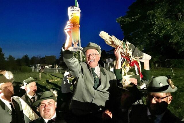 Detlef Busemann aus Unna-Stockum hält ein großes Bier in der Hand, seine Schützenbrüder tragen ihn auf den Schultern.