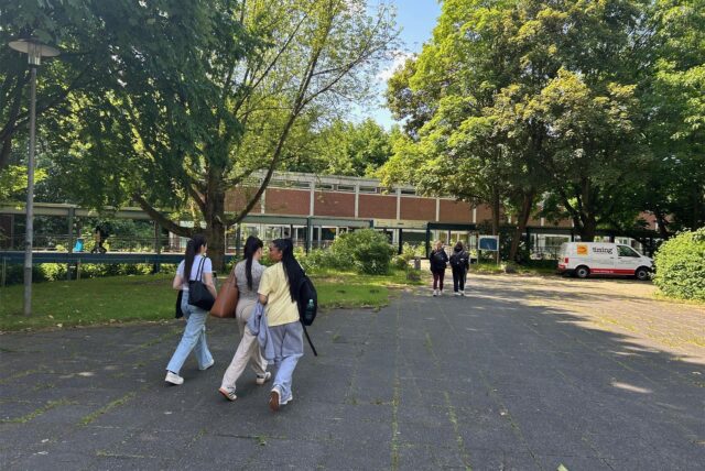 Jugendliche laufen am Hauptgebäude des früheren Robert-Schumann-Berufskollegs in Dortmund vorbei.