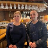 Das Bild zeigt das Restaurant „Hörder Treff“ mit seiner Außenbestuhlung. Auf der rechten Seite sind zwei Personen vor einem Tresen mit Gläsern zu sehen.