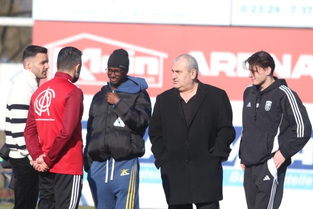 Imdat Acar steht mit Spielern vom Lüner SV auf dem Sportplatz.