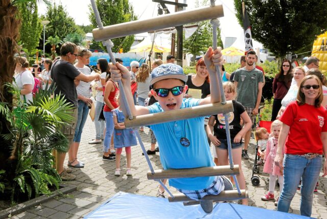 Ein Junge in blauem Shirt und mit blauer Kappe klettert beim Hafenfest in der Marina Rünthe in Bergkamen eine Strickleiter hinauf.