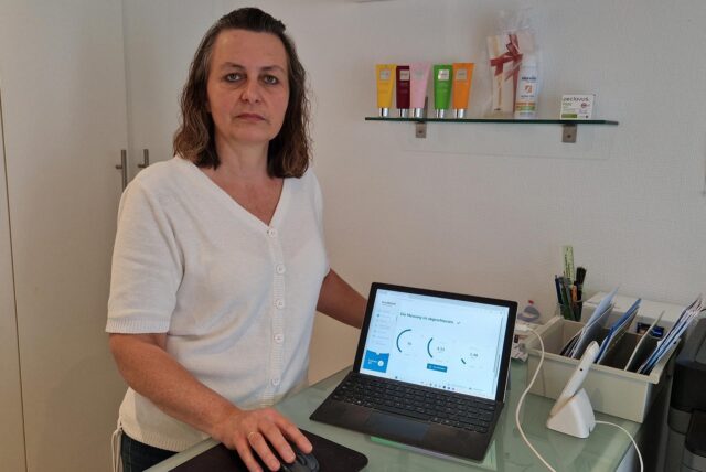 Anja Weiskamp steht an der Rezeption ihrer Fußpflegepraxis in Dortmund-Holthausen. Neben sich ist ein Tablet, dass die Internetverbindung testet.