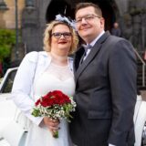 Die Eheleute Anna und Manuel Brücker stehen nach ihrer Trauung vor dem Recklinghäuser Rathaus. Hinter ihnen ist ein weißer VW Käfer Cabrio zu erkennen.