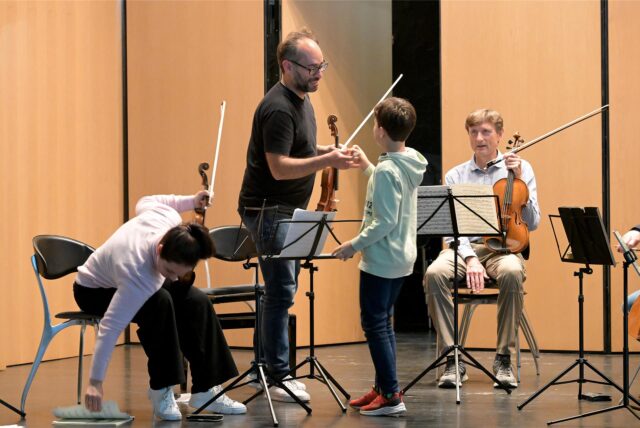 Familiensache: Der Sohn von Giovanni Guzzo (stehend) und Mirijam Contzen assistiert auf der Bühne im Theater des Schlosses Cappenberg. Klar, dass auch er selbst schon Geiger ist.