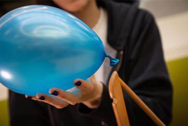 Eine Person hält einen blauen Luftballon.