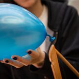 Eine Person hält einen blauen Luftballon.