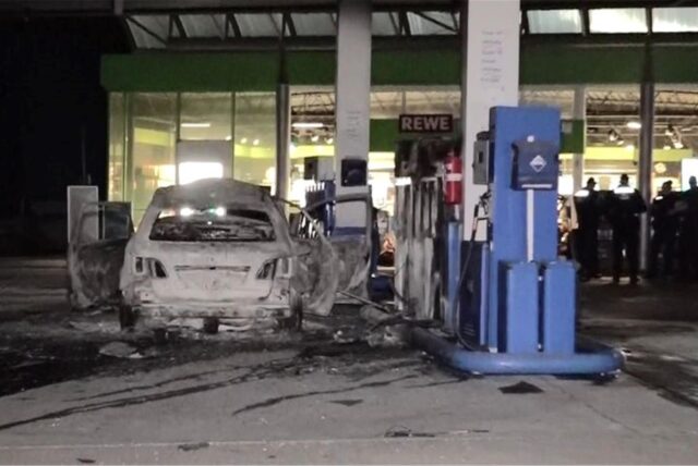 Ein ausgebranntes Fahrzeug steht an einer Zapfsäule auf einer Tankstelle. Ein polizeibekannter Mann sorgt am Samstagabend für einen Brand an einer Tankstelle in Hannover. Das SEK ist im Einsatz.