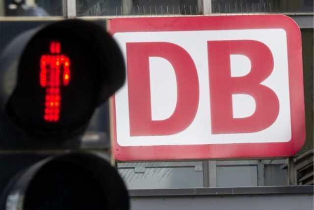 Eine Fußgängerampel, vor dem Logo der Deutschen Bahn (DB) am Münchner Hauptbahnhof, leuchtet Rot.