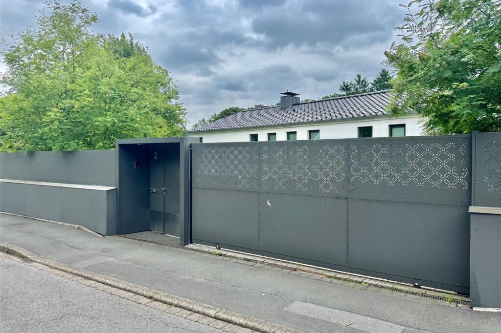 Ein hoher Zaun vor einem Haus an der Straße Ein hoher Zaun vor einem Haus an der Straße