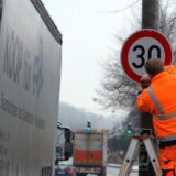 Ein Arbeiten mit Warnweste montiert ein Tempo-30-Schild.
