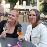 Zwei Frauen sitzen in der Lüner Innenstadt an einem Tisch und trinken aus Weingläsern.