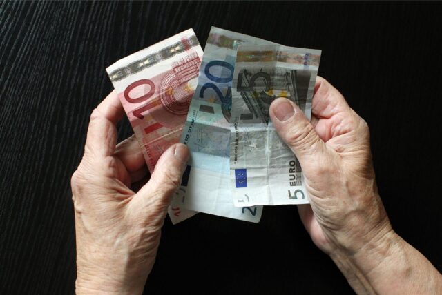 Ein älterer Mensch hat Geldscheine in der Hand.