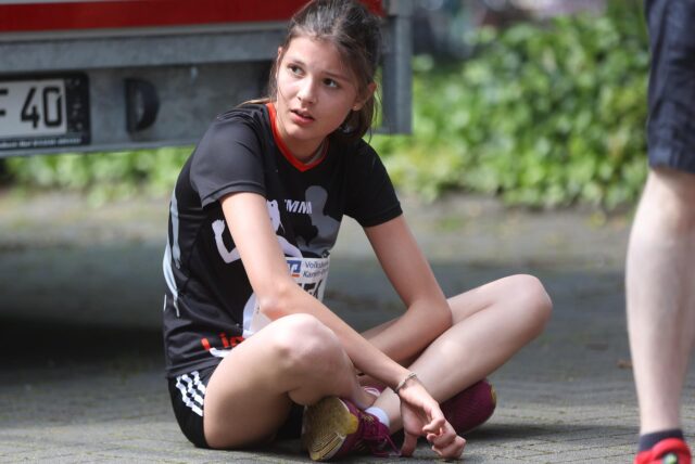 Läuferin sitzt im Schatten.