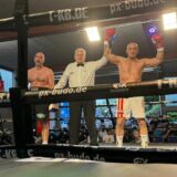 Michael Oleschak (r.) in Siegerpose im Ring neben dem Kampfrichter und seinem Kontrahenten.