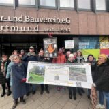 Demonstrierende Mitglieder der Nachbarschaftsinitiative Althoffblock mit einem Transparent vor der Geschäftsstelle des Spar- und Bauvereins.
