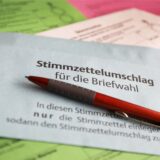 Stimmzettel und ein Umschlag für die Briefwahl liegen auf dem Tisch.