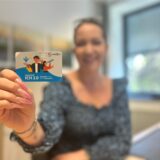 Mitarbeiterin des Kreises Unna hält die „UpdateCard ICH 2.0“ in die Kamera