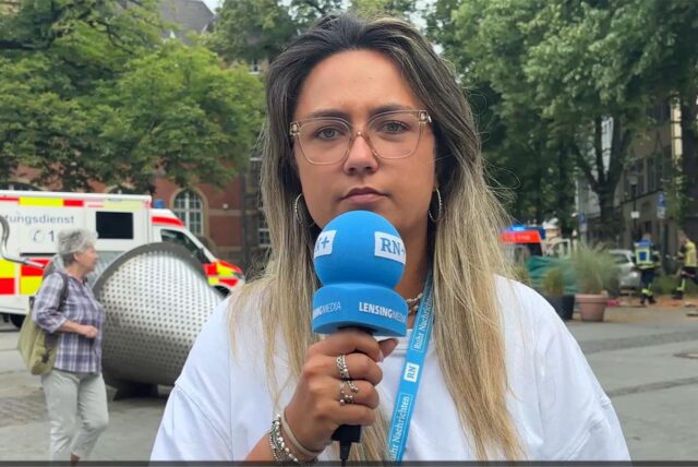 Ruhr-Nachrichten-Reporterin Leandra Stampoulis steht auf dem Postplatz in Schwerte. Im Hintergrund sind Rettungsfahrzeuge zu sehen.