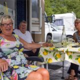 Drei Personen an einem Tisch auf einem Campingplatz.