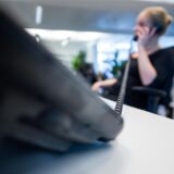 Eine Frau sitzt an einem Schreibtisch und telefoniert.