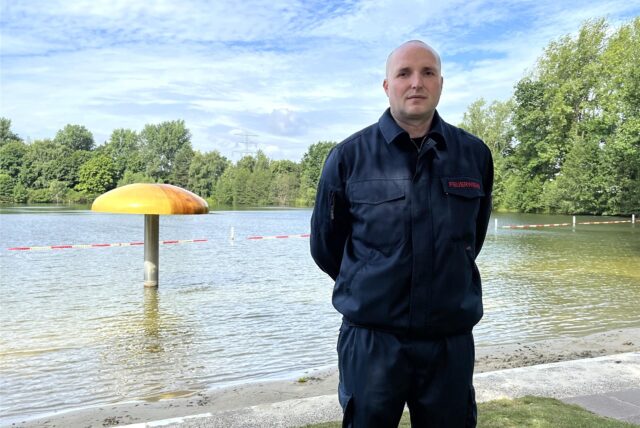 Ein Feuerwehrmann steht vor einem Naturfreibad in Marl.