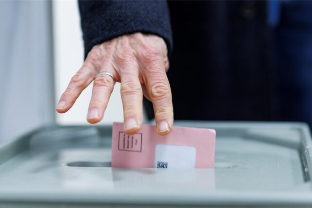 Ein Mann wirft seine Wahlunterlagen in eine Wahlurne.