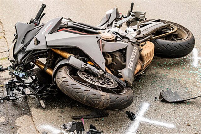 Ein Motorrad liegt nach einem Unfall auf der Fahrbahn. Herumliegende Trümmerstücke deuten auf einen heftigen Zusammenstoß hin.