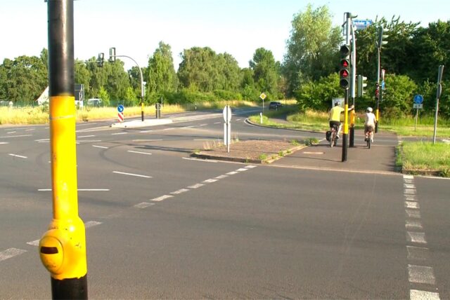 Blick auf die Kreuzung Brackeler Straße, Asselner Straße in Dortmund-Asseln. Schwarz-gelb besprühte Ampelmasten sind zu erkennen, sowie Radfahrer die an die Ampelmasten lehnen.
