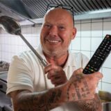 Gastronom Dirk Lasarz steht mit einer Kelle und einer Fernsehfernbedienung in der Küche des Kaiserhofs.