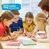 Symbolbild: Kinder lernen gemeinsam am Tischkreis mit einer Lehrerin.