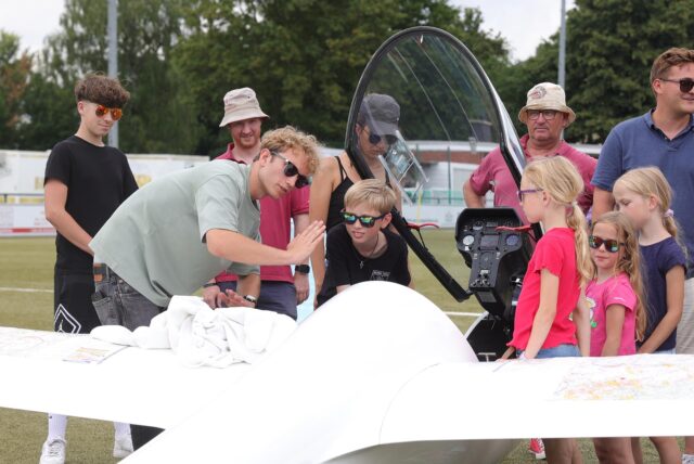 Ein Mann zeigt Kindern ein Segelflugzeug