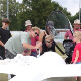 Ein Mann zeigt Kindern ein Segelflugzeug
