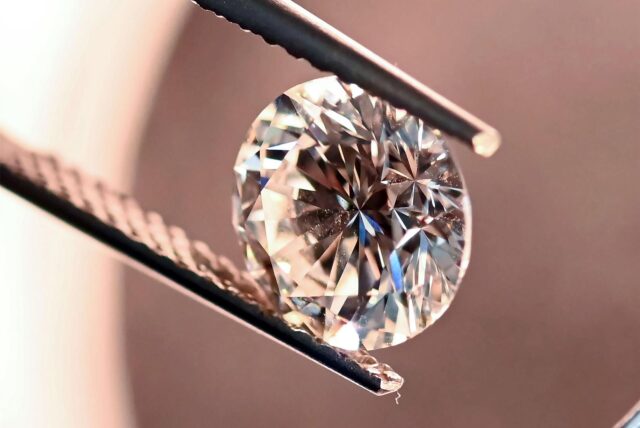 Eine Pinzette hält einen Diamanten.