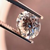 Eine Pinzette hält einen Diamanten.