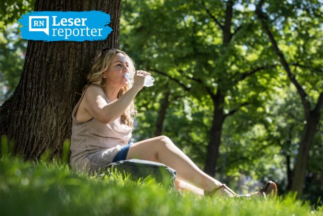 Symbolbild zu Hitze in Dortmund: Eine Frau sitzt im Schatten unter einem Baum und trinkt Wasser