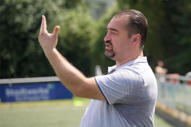 Ein Trainer gestikuliert am Spielfeldrand.