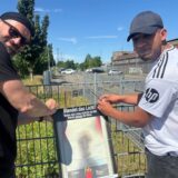 Peter Blaschke vom VSI und ein Jugendlicher hängen ein Plakat am Zaun am Bahnhog Schwerte auf.