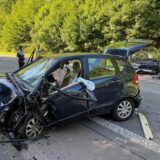 Zwei Autos stehen nach einem Unfall auf der B54 in Hagen auf der Straße. Polizisten untersuchen die Unfallstelle.