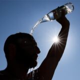 Ein Mann kühlt sich bei sommerlichen Temperaturen ab, in dem er sich eine Flasche mit Wasser über den Kopf schüttet.