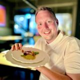 Ruhr-Nachrichten-Reporter Fabian Hollenhorst hält einen Teller aus dem Menü des Restaurants SchwarzGold in Dortmund in die Kamera.
