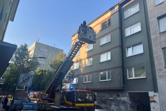 Einsatzkräfte der Feuerwehr stehen im Korb der Drehleiter vor einem Haus im Unionviertel in Dortmund.