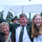Schützenkönig Martin Fallenberg steht im Kreise seiner Familie und jubelt mit erhobenen Armen.