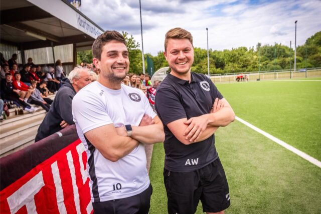 Ein Trainer blickt lachend in die Kamera.